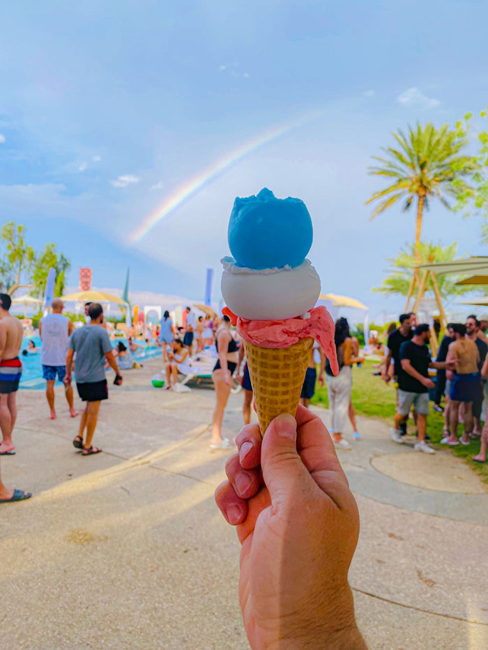 יד מחזיקה בכדור גלידה , טעמי גלידה בטעם פרוטי, תות וקוקוס באירוע חברה בים המלח